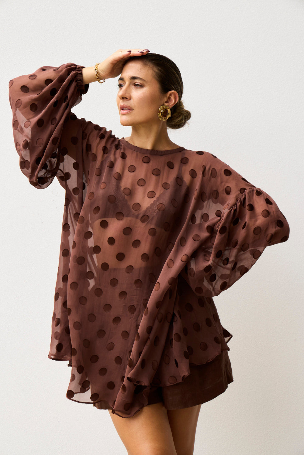 Woman wearing a brown polka dot dress against a white background