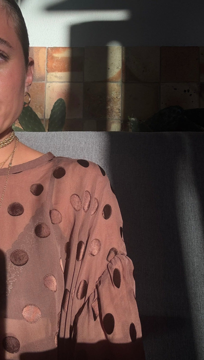 Woman wearing a brown polka dot dress with a blurred background