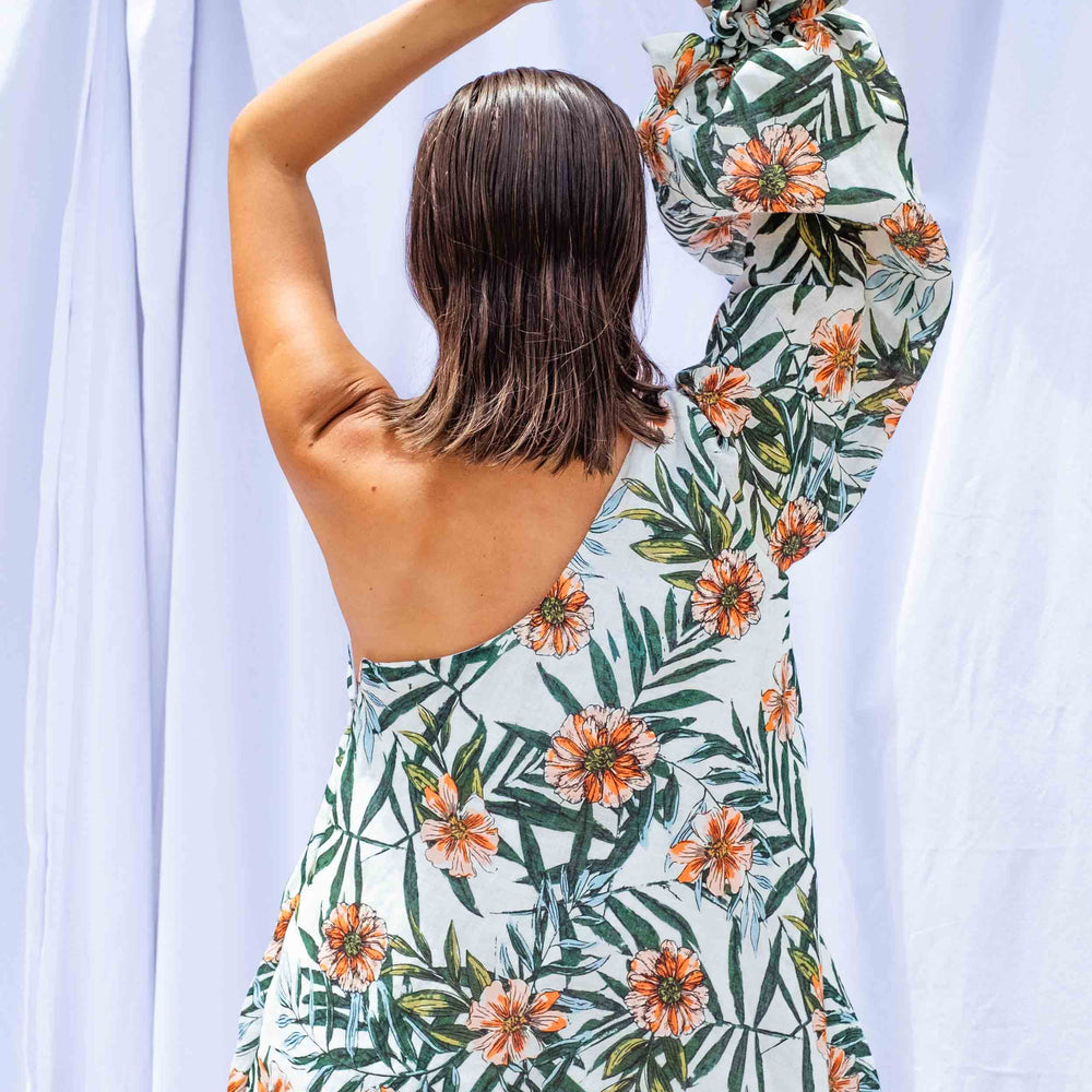 
                      
                        Woman facing away from camera, wearing Palm Balloon Sleeve Swing Dress by Isabella Longginou. She has both arms above her head.
                      
                    
